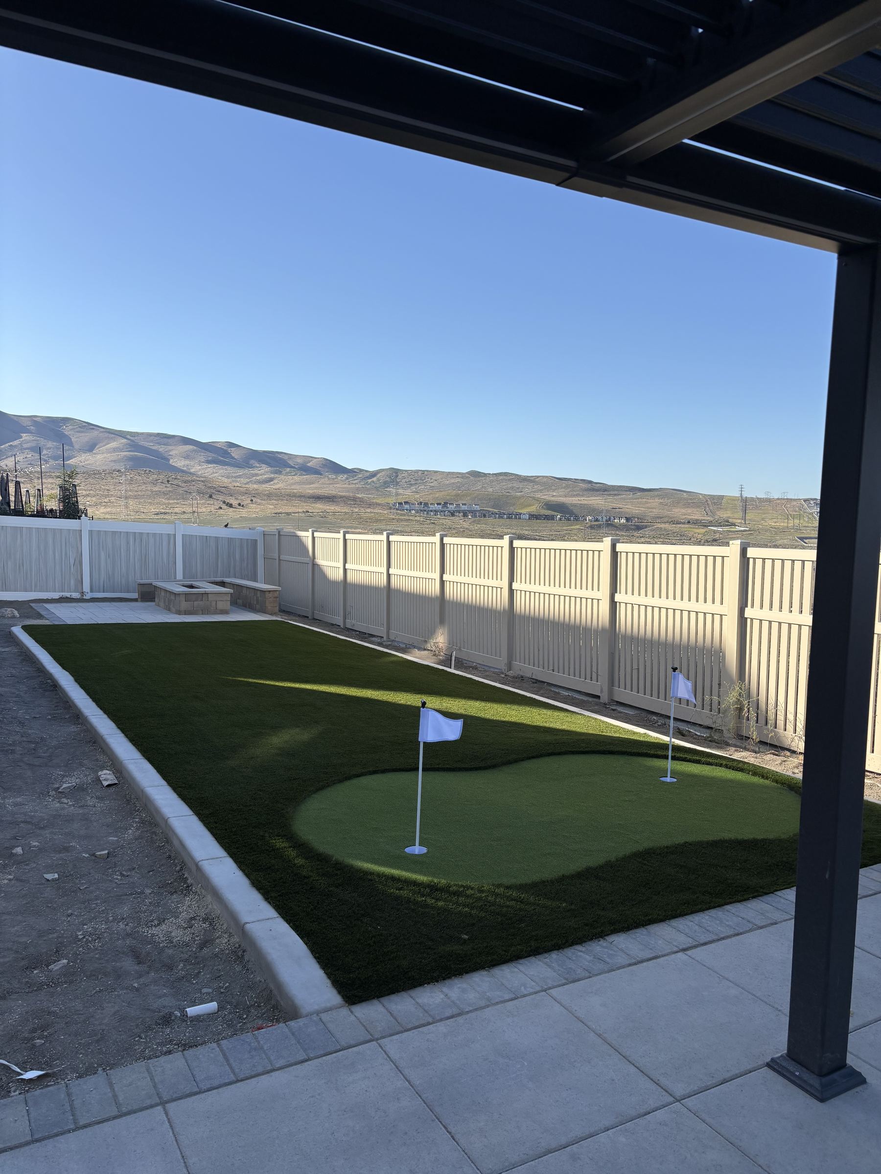 Putting green at dusk next to a stone fire pit with mountain view